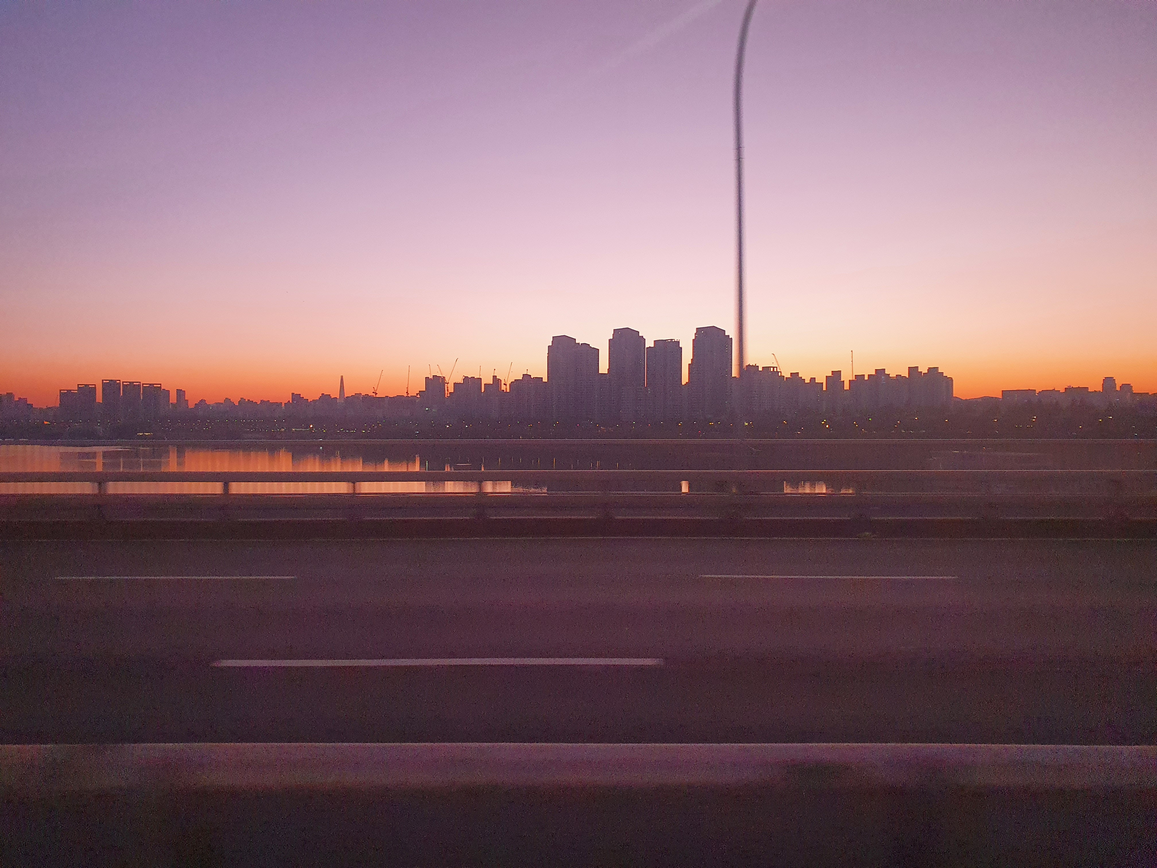 A twilight skyline beyond a riverside walkway.